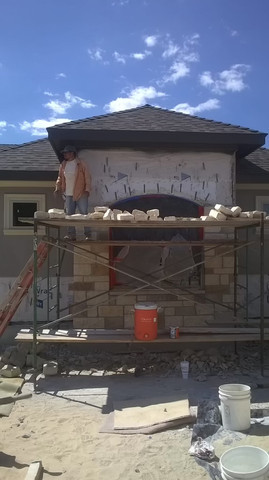 Stone veneer fireplace installation on home exterior